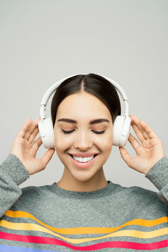 Young woman enjoying music with wireless headphones and a joyful smile.