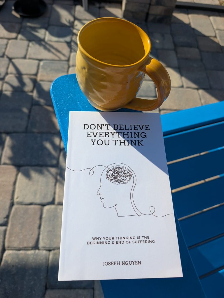 "Dont believe everything you think" book and a yellow mug, outside